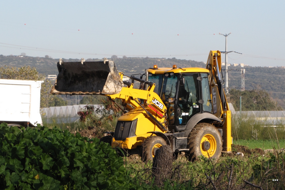 Трактор JCB 3CX ECO, строительство автобусного терминала на востоке Хайфы. Израиль, перекресток Ягур